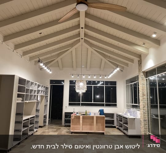 חדר עם מדפים, שולחן, בקבוקי ניקוי ושקיות פלסטיק